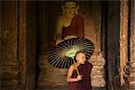 Portrait of young novice monks with umbrella inside ancient Buddhist temple, Bagan, Myanmar.