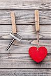 Heart and key hanging on a string, shot on wooden background