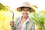 Portrait of a happy mature Burmese female farmer with thanaka powdered face who works in the field.