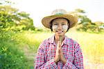 Portrait of a young Burmese female farmer with thanaka powdered face in blessing gesture.