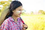 Portrait of a young Burmese girl farmer with thanaka powdered face working in field.
