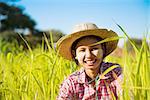 Portrait of a young Asian Myanmar farmer with thanaka powdered face working in the paddy field.
