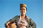 Portrait of mature Asian Burmese traditional female farmer carrying clay pot, Bagan, Myanmar