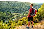 Men walk along the hill with backpack and with white clouds and mountains on background