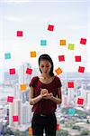 Young woman working as secretary in office, leaning on big skyscraper window. She writes adhesive notes with tasks on window.