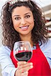 A beautiful latina hispanic girl or young woman drinking red wine at home toasting to camera