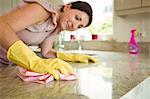 Woman cleaning kitchen counter with cloth in rubber gloves