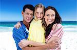 Cute family smiling and hugging on the beach