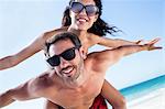 Boyfriend giving piggy back to his girlfriend on the beach