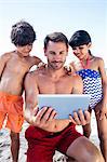 Father and children using tablet on the beach