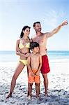 Cute family looking at something on the beach