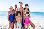 Cute family standing and smiling on the beach