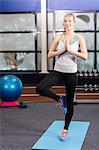 Smiling woman doing yoga exercise at the gym