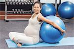 Pregnant woman leaning back on fitness ball at the leisure center