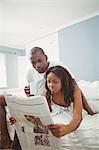 Ethnic couple reading the news in the bedroom