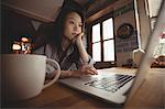 Brunette using laptop in the kitchen at home