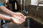 Pretty woman washing her hands in the kitchen