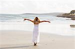 Beautiful blonde woman relaxing with arms outstretched in the coastline