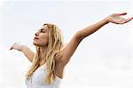 Beautiful blonde woman with arms outstretched in the coastline