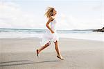 Beautiful blonde woman skipping in the coastline