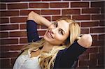 Blonde woman relaxing in chair on brick wall