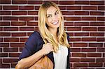 Portrait of smiling blonde woman on brick wall