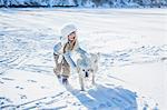 Cute girl playing with dog on a beautiful snowy day
