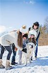 Family playing with dog on a beautiful snowy day