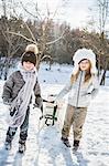 Brother and sister playing with sled on a beautiful snowy day