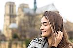 Side view of young woman, Notre Dame Cathedral in background, Paris, France