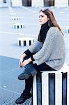 Young woman sitting on striped concrete stool, Le Palais Royal, Paris, France