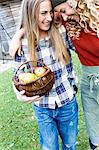 Two friends with arms round each other, one carrying basket of apples