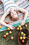 Woman lying on striped rug with basket of apples
