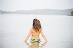 Woman in the sea, wearing bikini, rear view