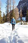 Rear view of young woman hiking through mountain snow, Austria