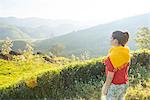 Young woman looking out at tea plantations near Munnar, Kerala, India