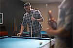 Man preparing to play pool, friend with beer in foreground