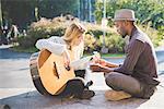Couple learning to play guitar in park