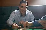 Man gambling key playing card game at pub card table