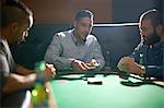 Male friends dealing playing card for game at pub card table