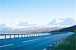 Empty road with snowcapped mountains on background