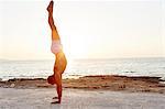 Man doing handstand on beach at sunset