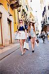 Mother and daughter with shopping bags walking in street