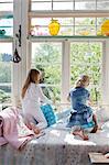 Rear view of two girls kneeling on bed