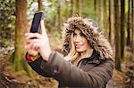 Beautiful blonde woman taking selfie in the woods