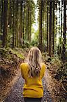 Beautiful blonde woman walking on road surrounded by forest