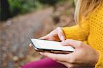 Beautiful blonde woman using smartphone in the woods