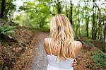Beautiful blonde woman wearing white dress in the woods