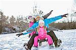 Family sitting on a sleigh on a beautiful snowy day