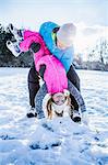 Father carrying his daughter who is overhead on a beautiful snowy day